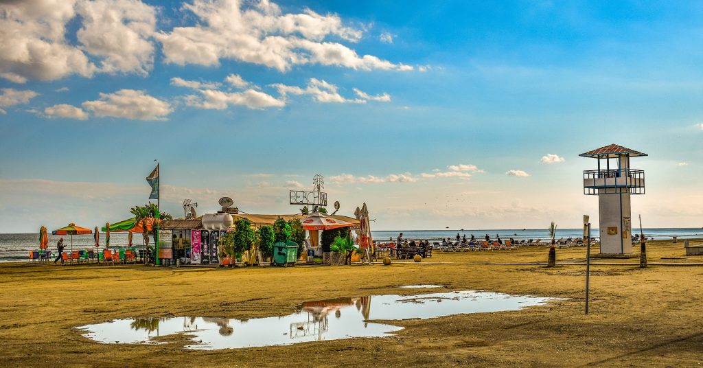 A colorful pop-up shop tent on a beach with blue skies.