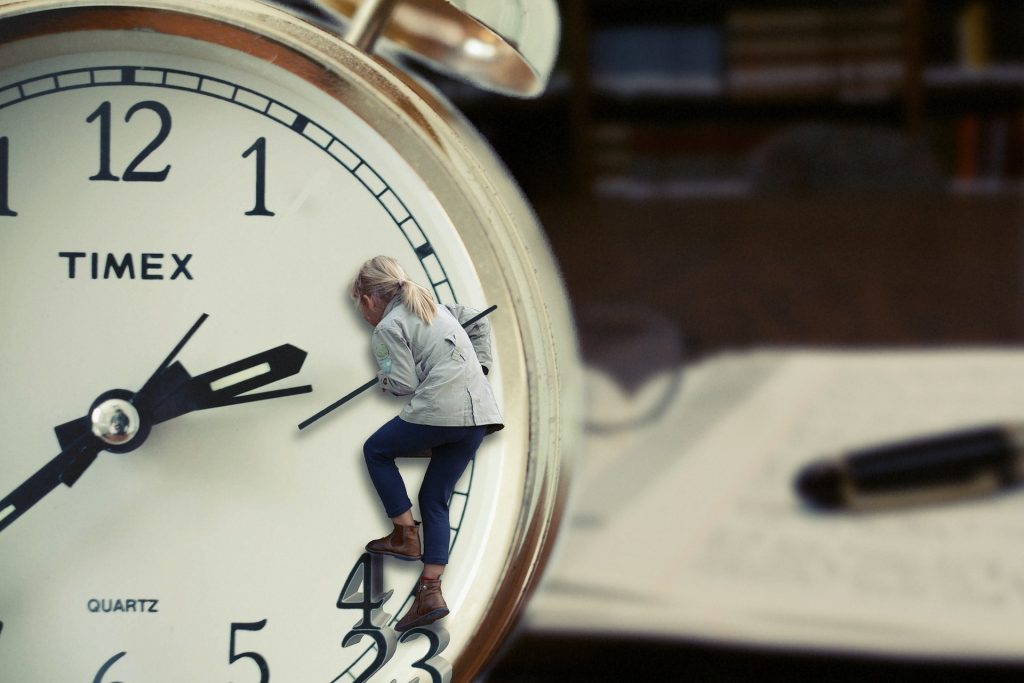 A woman inside a clock trying to climb up its numbers.