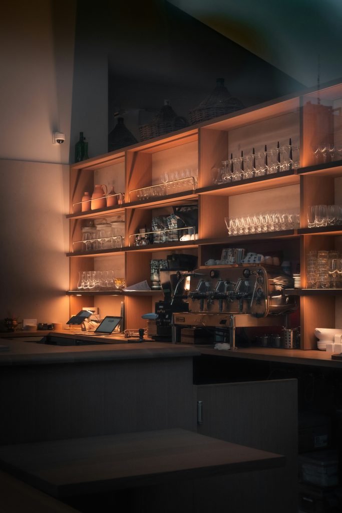 A softly illuminated lab space with many shelves of glass beakers and a wide table full of equipment equipment.