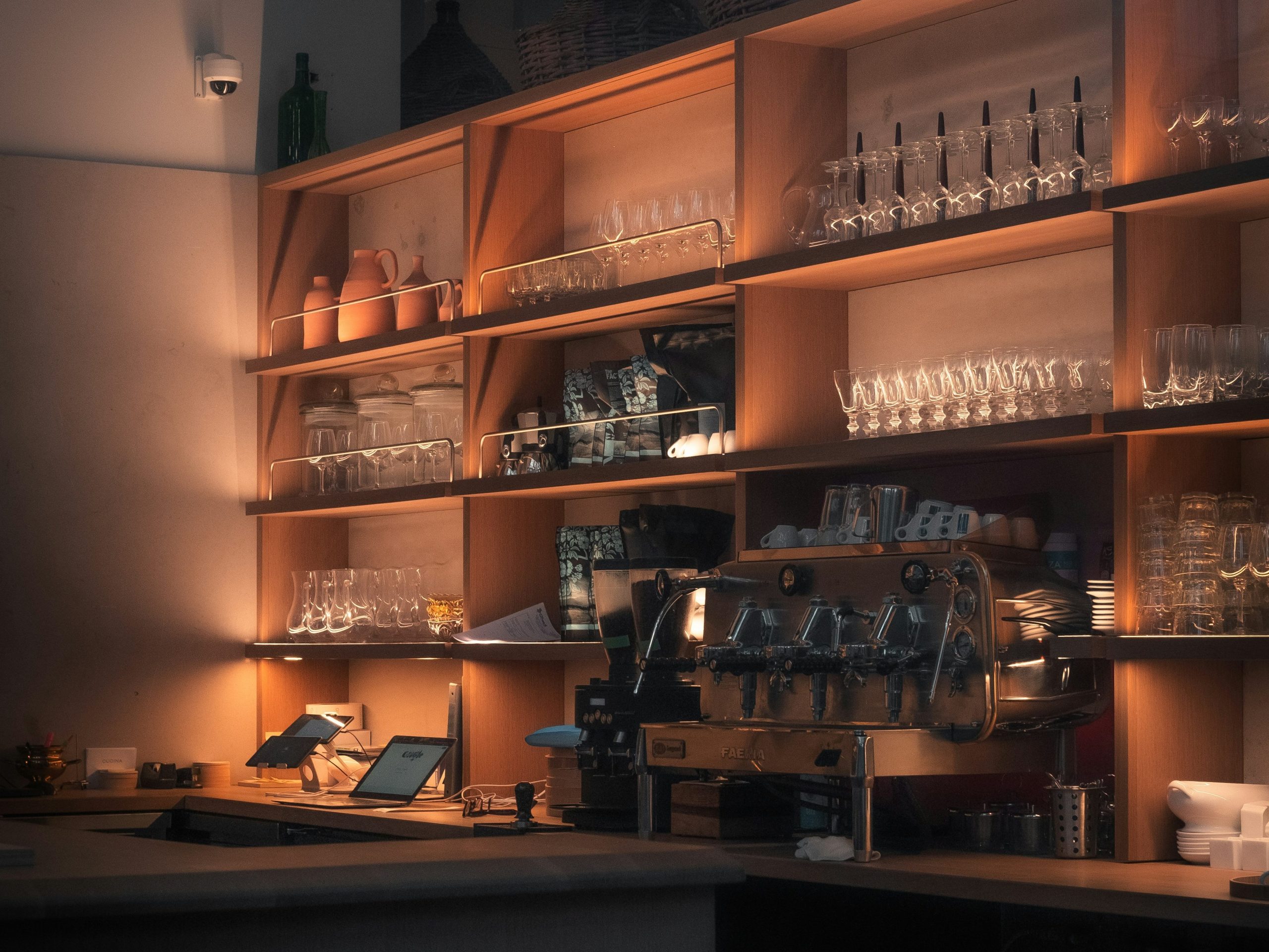 A softly illuminated lab space with many shelves of glass beakers and a wide table full of equipment equipment.