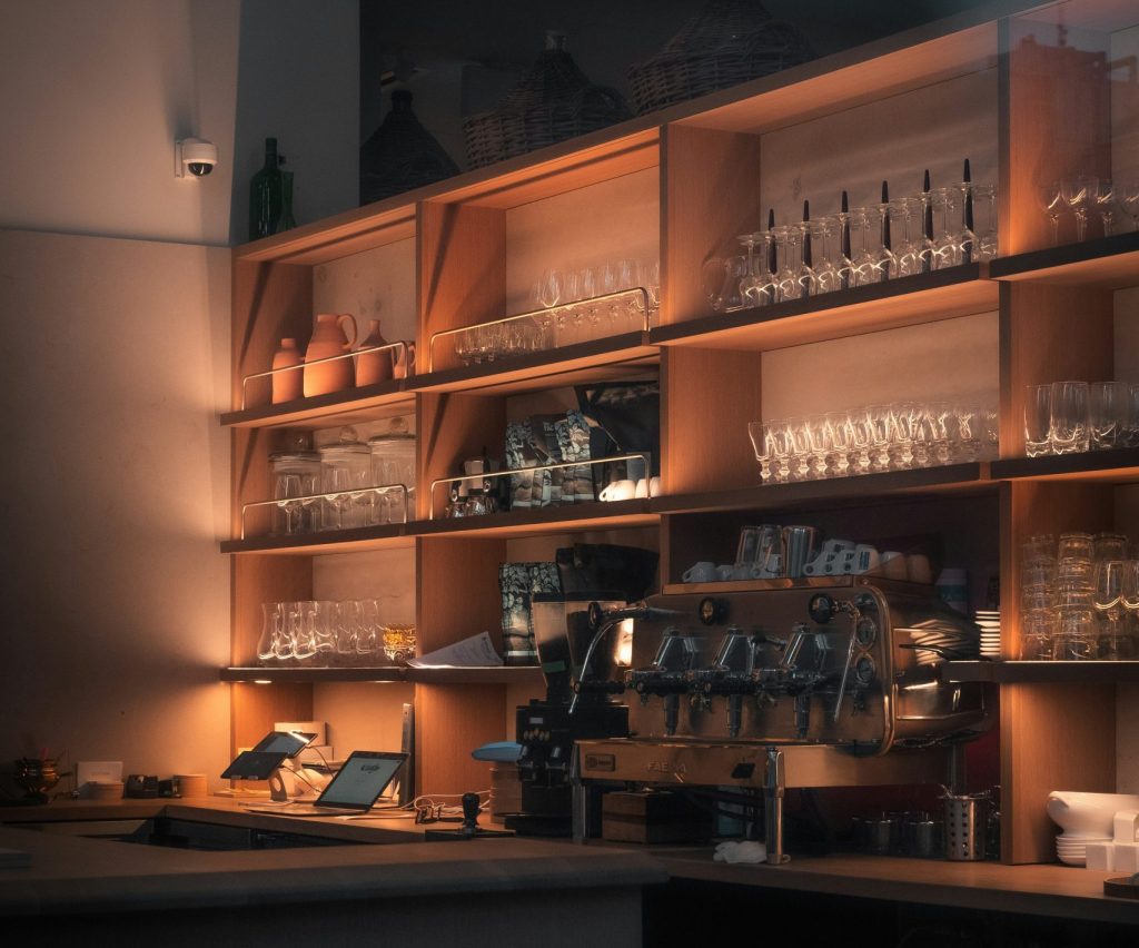 A softly illuminated lab space with many shelves of glass beakers and a wide table full of equipment equipment.